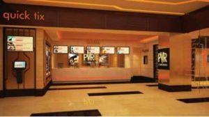 Modern cinema ticket counter with sleek, illuminated design. Digital displays show movie options. Warm lighting creates an inviting atmosphere.